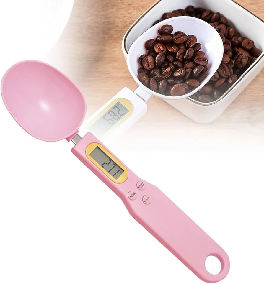 Pink digital measuring spoon with a bowl of coffee beans on a white background