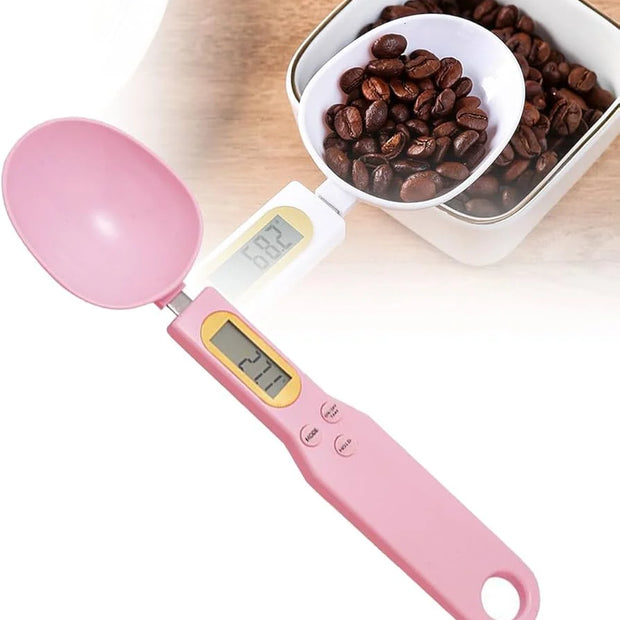 Pink digital measuring spoon with a bowl of coffee beans on a white background