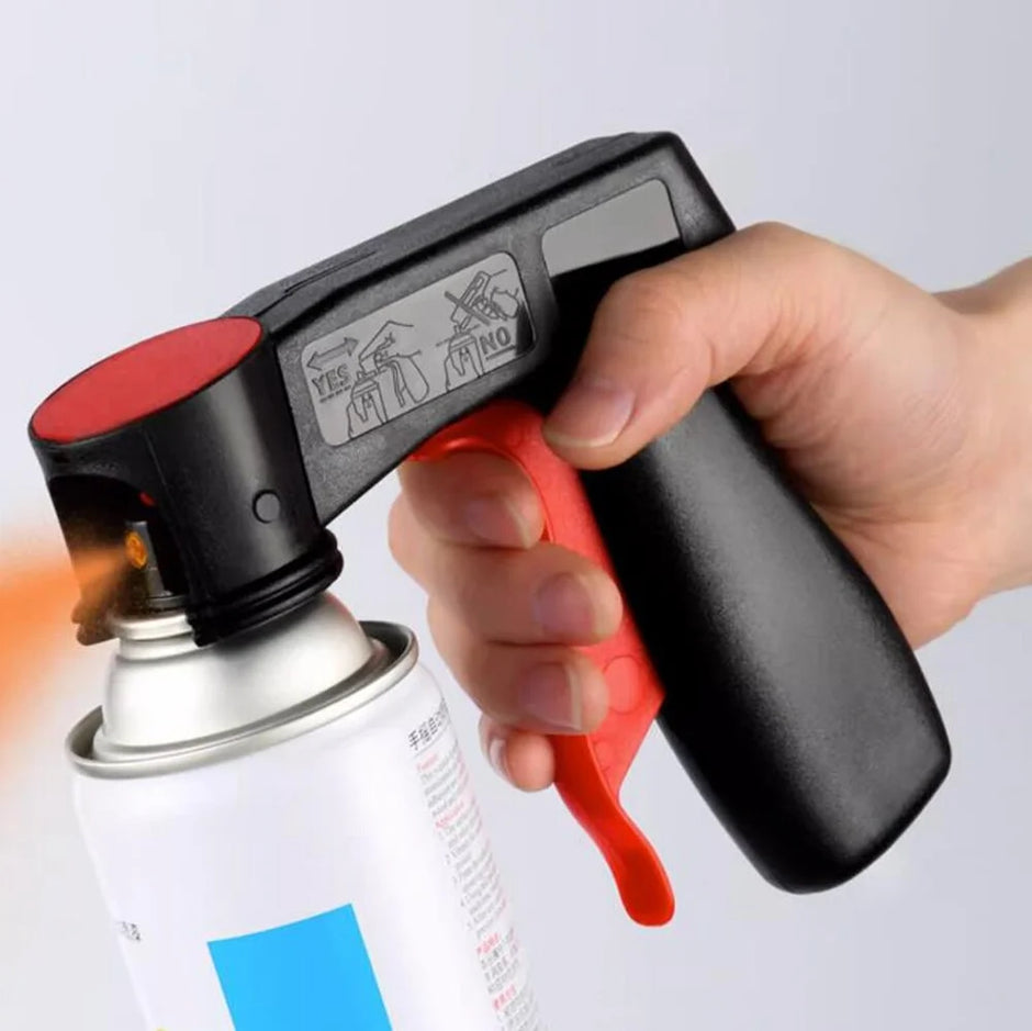 Hand holding a spray gun with a red and black design, spraying a white canister.