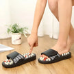 Black massage slippers with beads on a wooden floor.