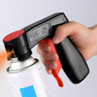 Hand holding a spray gun with a red and black design, spraying a white canister.