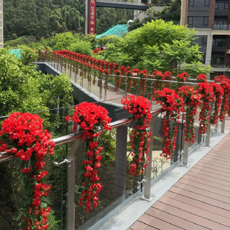 Decorative red flowers on a railing with greenery and buildings in the background