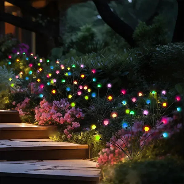 Colorful string lights illuminating a garden pathway at night.