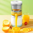 Juicer with oranges and a glass of juice on a wooden board against a green background